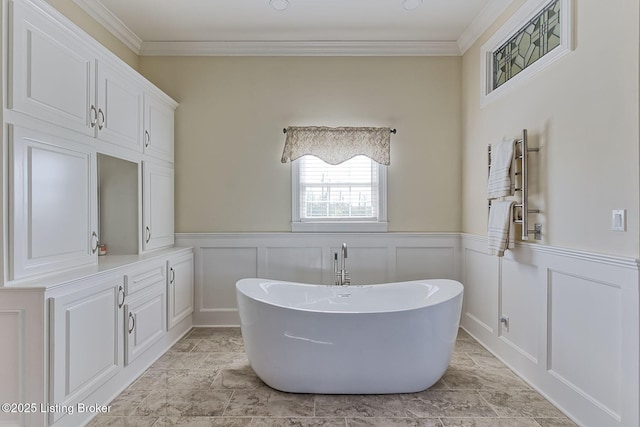 bathroom with crown molding, wainscoting, a decorative wall, and a soaking tub