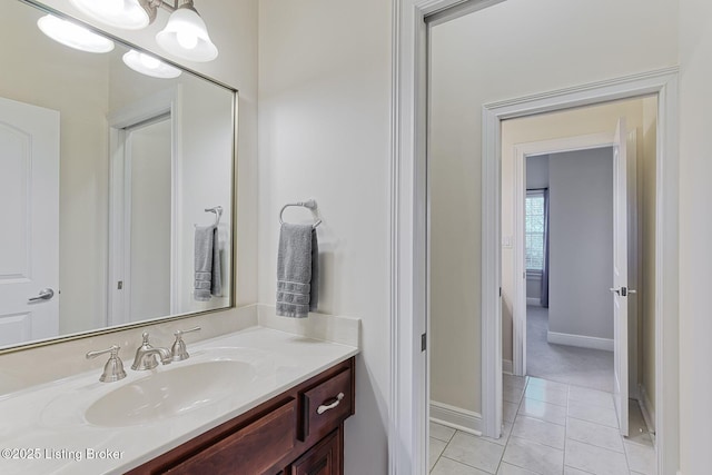 bathroom with an inviting chandelier, baseboards, tile patterned flooring, and vanity