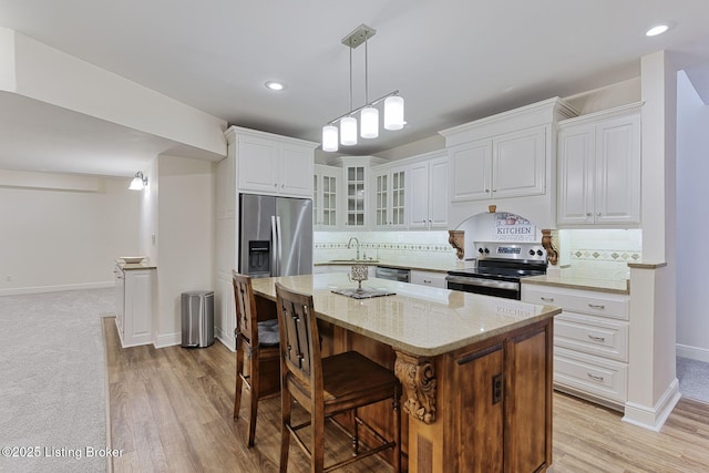 kitchen featuring stainless steel appliances, baseboards, white cabinetry, a kitchen bar, and glass insert cabinets