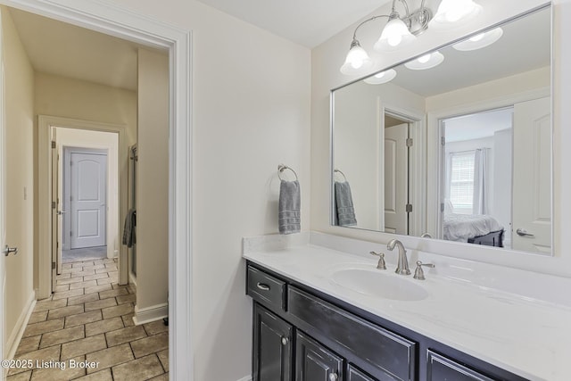 ensuite bathroom with connected bathroom, baseboards, a chandelier, and vanity