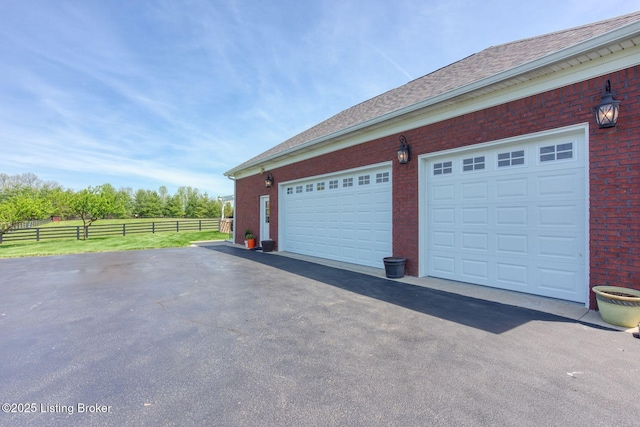 garage featuring fence and aphalt driveway