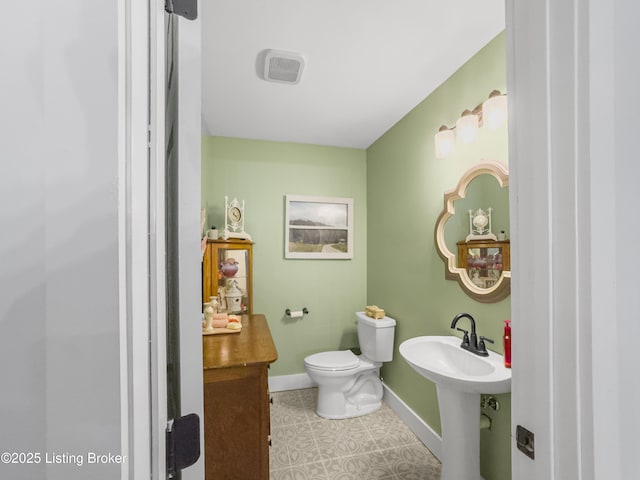 half bathroom featuring toilet, baseboards, and a sink