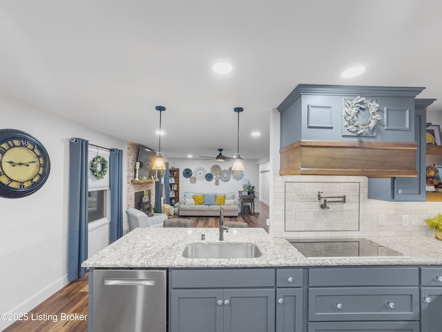 kitchen featuring decorative backsplash, a large fireplace, a sink, dark wood-style floors, and open floor plan
