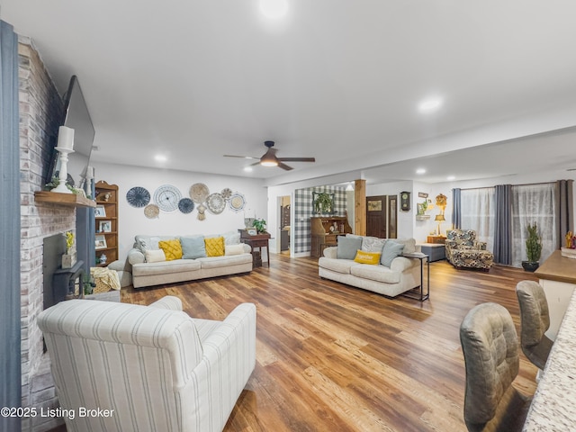 living area with ceiling fan, a fireplace, recessed lighting, and wood finished floors