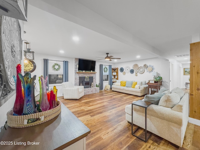 living room featuring ceiling fan, visible vents, a brick fireplace, wood finished floors, and recessed lighting