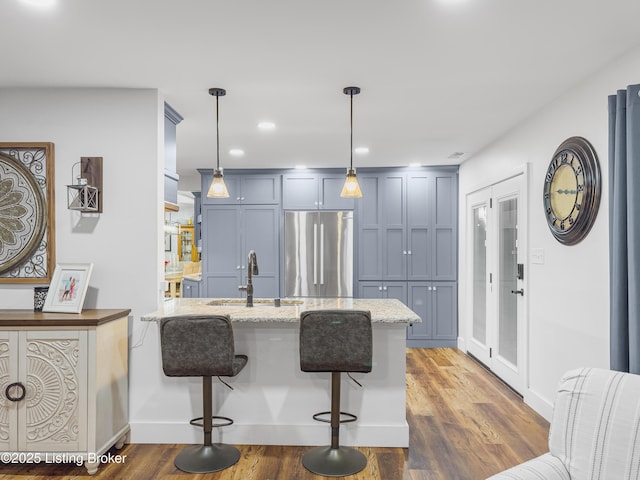kitchen with light stone countertops, a breakfast bar, stainless steel fridge, a sink, and a peninsula