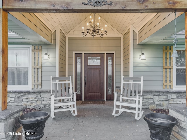 doorway to property featuring covered porch and stone siding