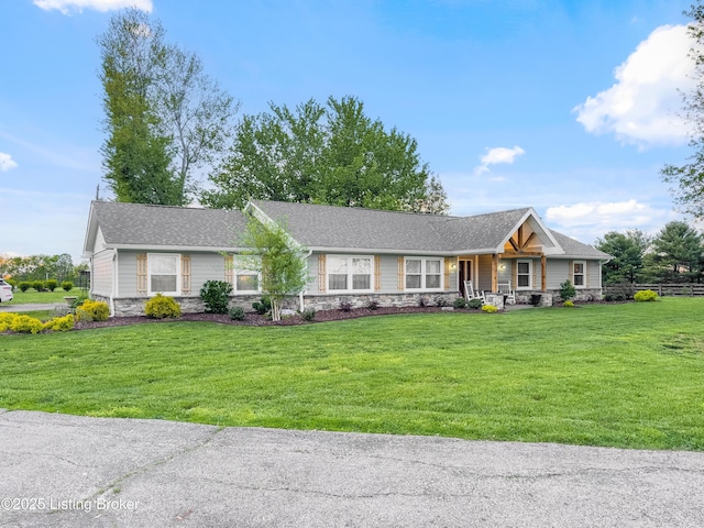 single story home featuring covered porch, a front yard, and stone siding