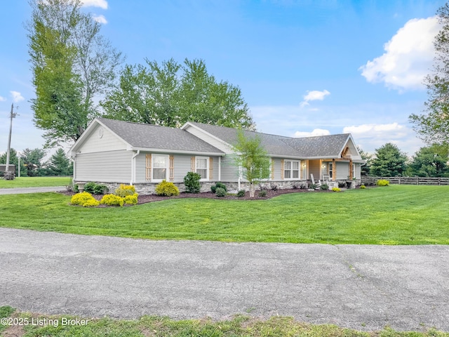 ranch-style house with fence, stone siding, and a front lawn
