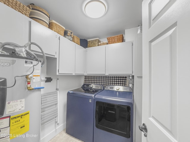 washroom with cabinet space, independent washer and dryer, and water heater