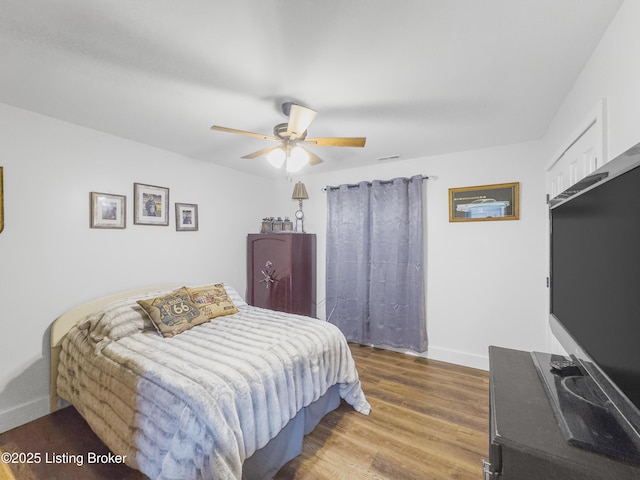 bedroom with baseboards, ceiling fan, wood finished floors, and visible vents