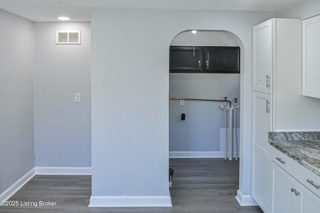 interior space featuring baseboards, dark wood finished floors, cabinet space, and visible vents