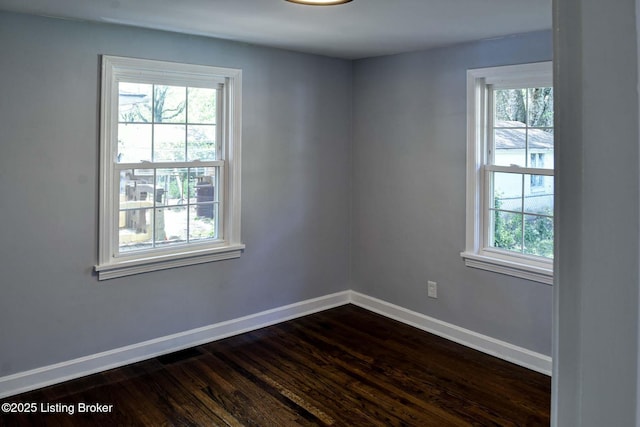 unfurnished room with baseboards, dark wood finished floors, and a wealth of natural light