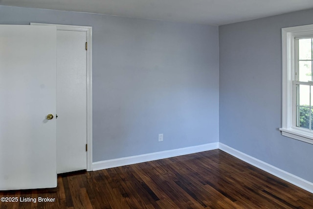 spare room featuring baseboards, dark wood-style flooring, and a healthy amount of sunlight