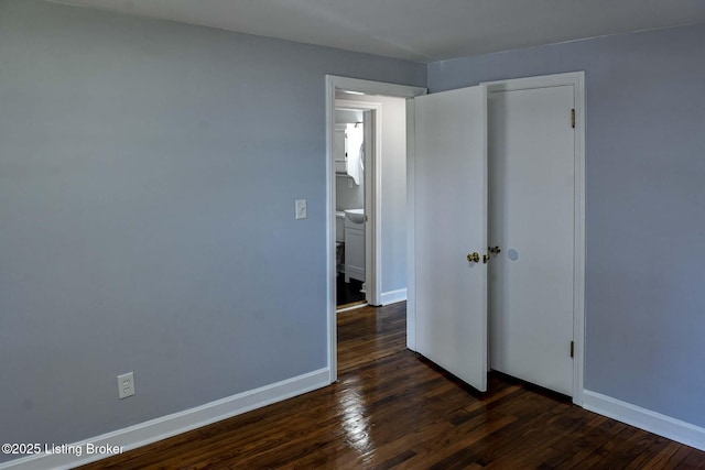 unfurnished bedroom featuring baseboards, dark wood finished floors, and a closet