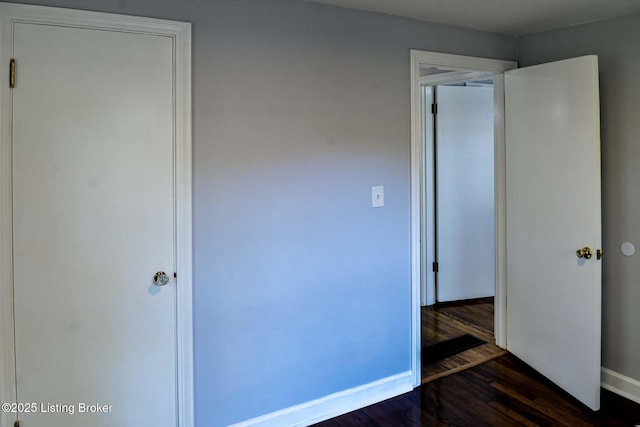 unfurnished bedroom with baseboards and dark wood-style flooring