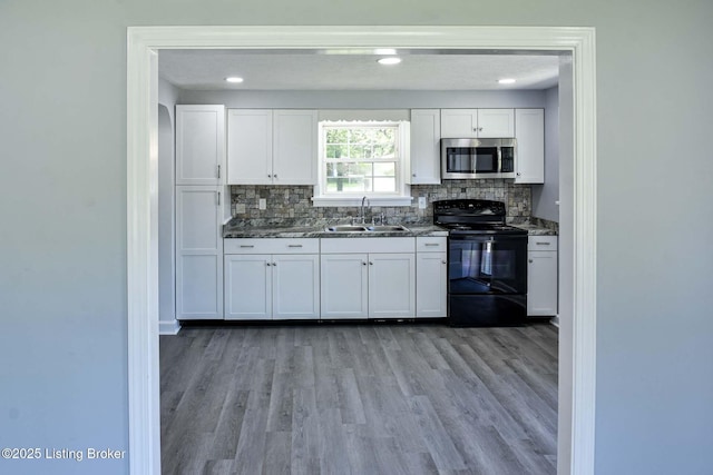 kitchen with electric range, stainless steel microwave, decorative backsplash, and a sink