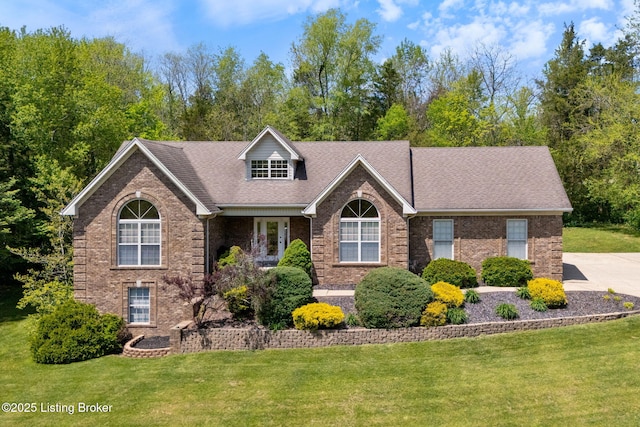 view of front of property featuring roof with shingles, a front lawn, and brick siding