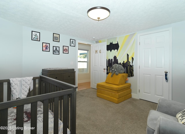 carpeted bedroom with baseboards, a textured ceiling, and a nursery area