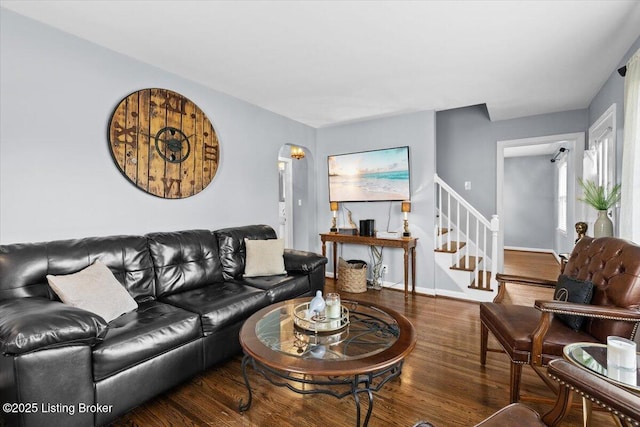 living room with baseboards, wood finished floors, and stairway