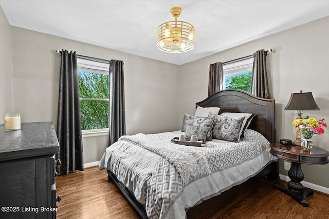 bedroom with baseboards, a chandelier, and wood finished floors