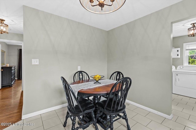 dining space with an inviting chandelier, baseboards, and washer and clothes dryer
