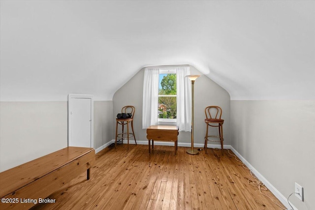 additional living space with light wood-style floors, baseboards, and vaulted ceiling