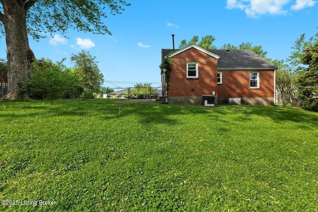 view of property exterior featuring central AC unit, fence, and a yard