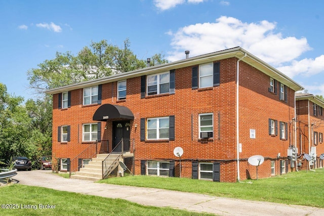 view of front facade featuring cooling unit, a front lawn, and brick siding