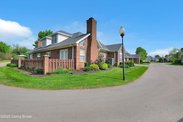 10002 Brownsboro Gardens Cir, Louisville, KY 40241 - view of home's exterior featuring fence, a chimney, brick siding, a shingled roof, and a lawn