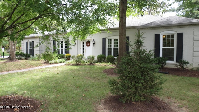 ranch-style house featuring brick siding, a shingled roof, and a front yard