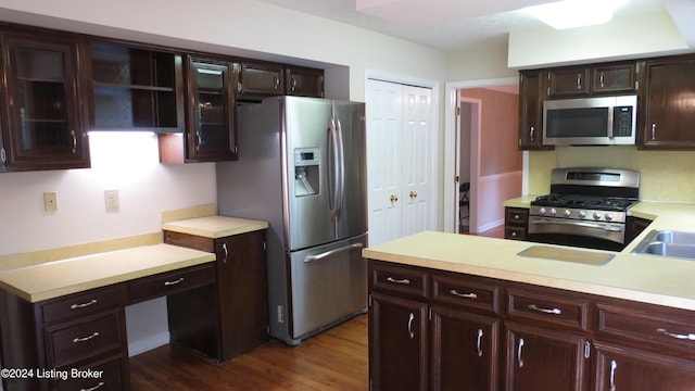 kitchen featuring dark wood-type flooring, light countertops, appliances with stainless steel finishes, and glass insert cabinets