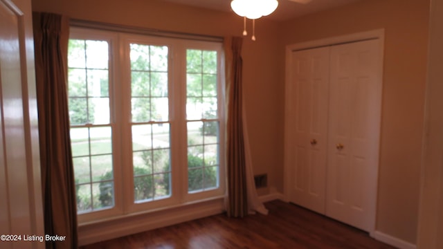 interior space featuring a ceiling fan, baseboards, a healthy amount of sunlight, and dark wood-type flooring