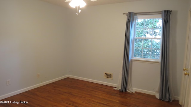 empty room featuring baseboards, ceiling fan, dark wood-style flooring, and visible vents