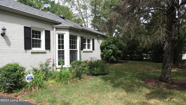 view of property exterior with a lawn, brick siding, and a shingled roof