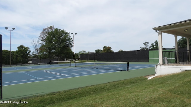 view of tennis court with a lawn, fence, and community basketball court