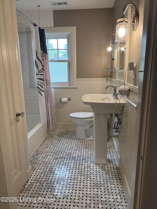 2302 Woodford Pl, Louisville, KY 40205 - bathroom featuring visible vents, a wainscoted wall, toilet, and shower / bath combo with shower curtain