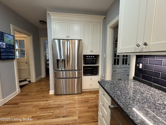 2302 Woodford Pl, Louisville, KY 40205 - kitchen with stainless steel fridge, light wood-style floors, dark stone counters, white cabinetry, and decorative backsplash
