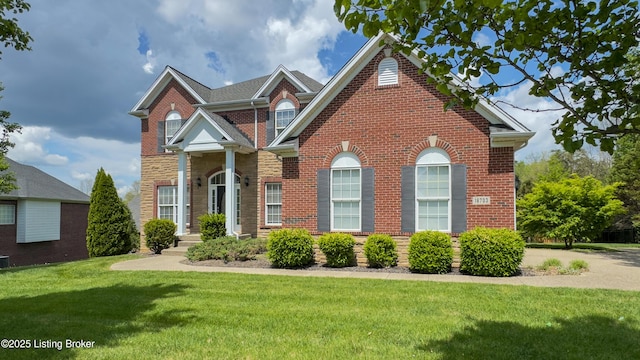 traditional home featuring brick siding, stone siding, and a front yard