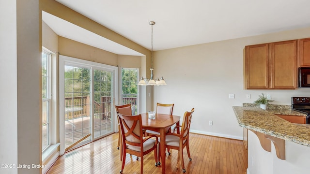 dining space with baseboards, light wood finished floors, and visible vents