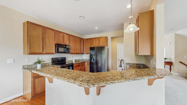 kitchen with light stone counters, baseboards, a peninsula, and black appliances