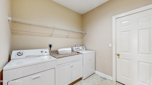 washroom featuring visible vents, baseboards, washing machine and clothes dryer, cabinet space, and light tile patterned floors