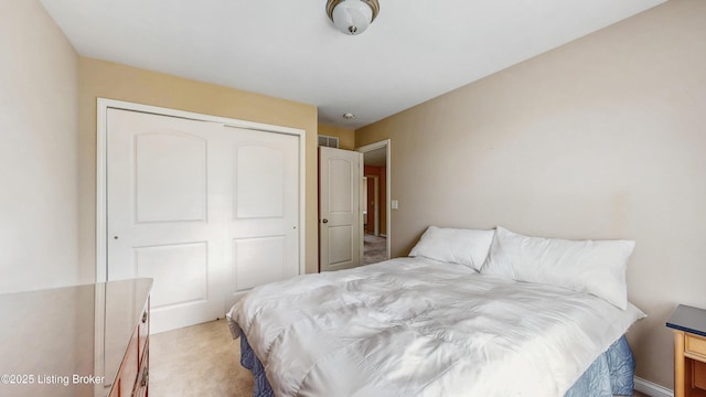 bedroom with light colored carpet, visible vents, and a closet