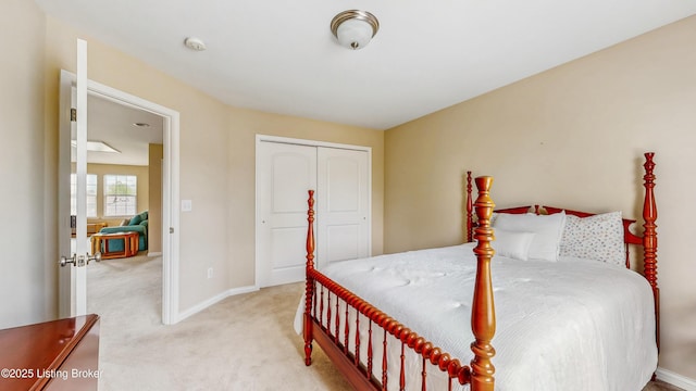 bedroom with a closet, baseboards, and light carpet