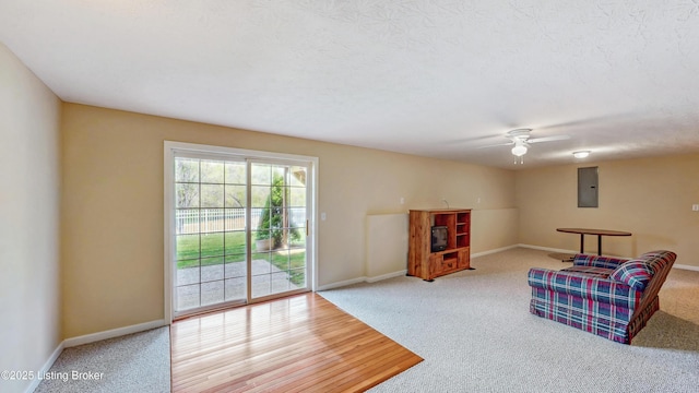 living area with ceiling fan, baseboards, carpet, and electric panel