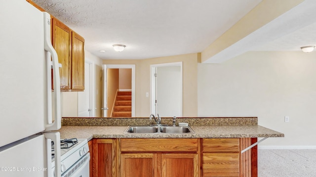 kitchen featuring a sink, a peninsula, brown cabinets, and white appliances