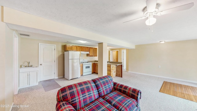 living room with a ceiling fan, baseboards, visible vents, and light carpet