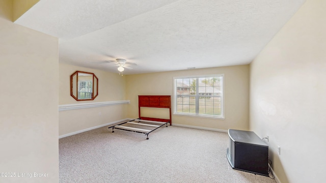 living area with baseboards, a ceiling fan, carpet flooring, and a textured ceiling