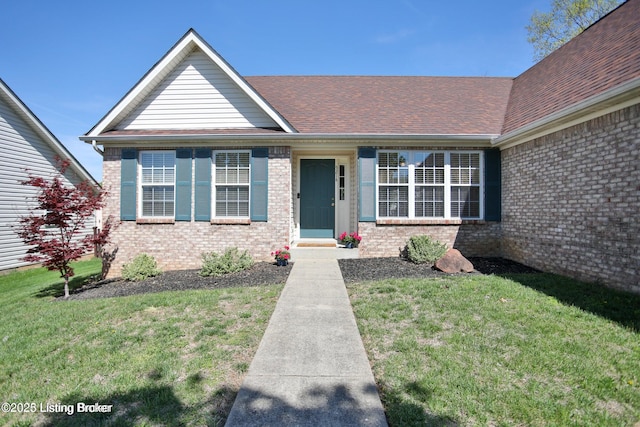 view of front of home with brick siding, roof with shingles, and a front lawn