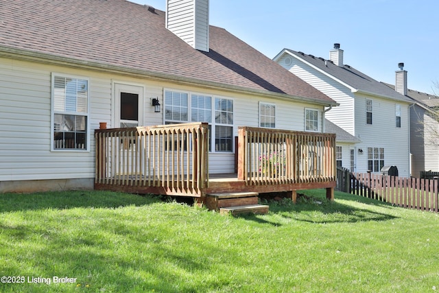 rear view of house with a lawn, fence, a wooden deck, and a chimney